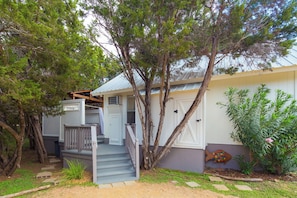 A residential property with a front porch, a staircase leading to the entrance, and a garden area with various plants.
