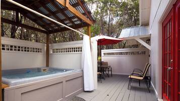 An outdoor hot tub area with a pergola, a covered seating area, and a red door.