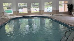 Une piscine intérieure à l’eau claire, entourée de grandes fenêtres qui offrent une vue sur l’extérieur.