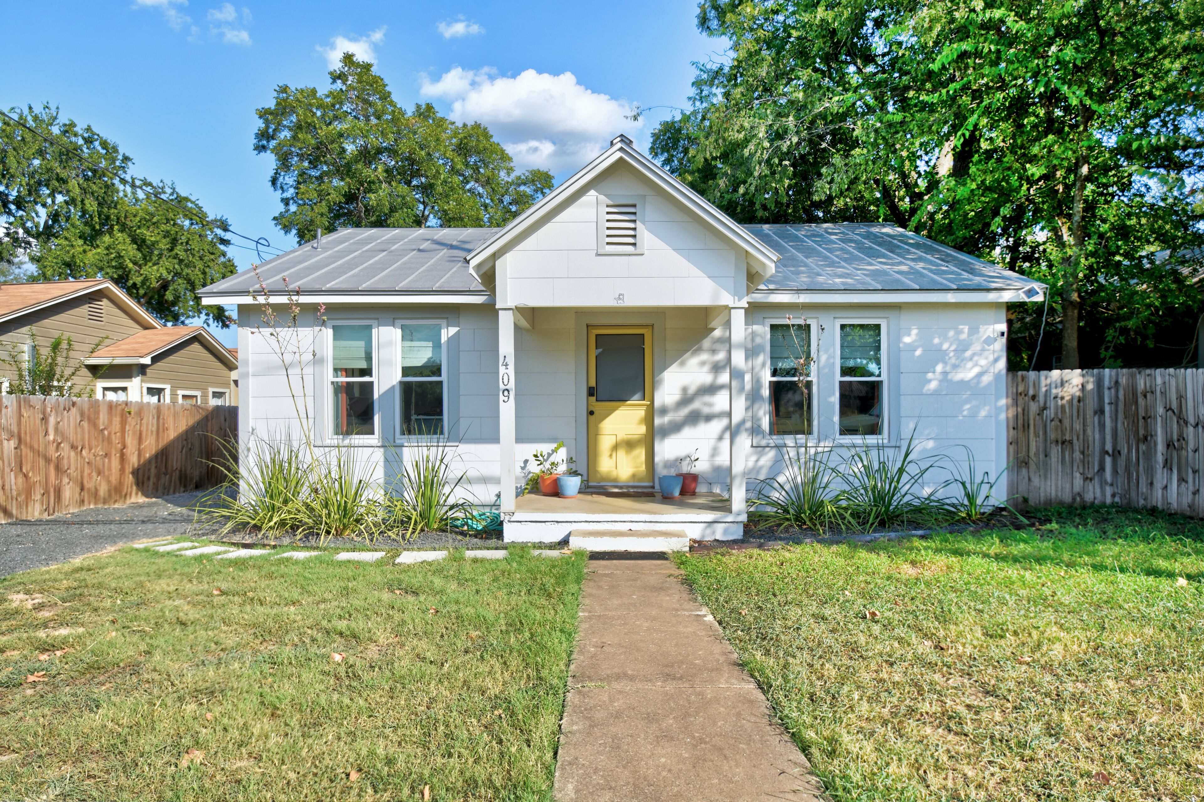A single-story house with a front porch, a visible number '409', and a small garden area.