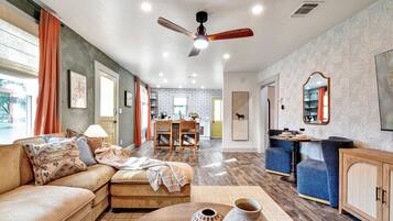 A living room with a sofa, coffee table, and a dining area with chairs and a table.