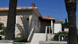 Un edificio de piedra con techo de tejas, una escalera y palmeras.