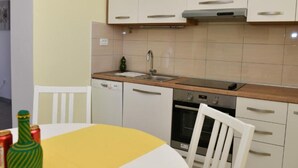 Una cocina compacta con armarios blancos, una encimera de madera, un fregadero, lavavajillas y horno.