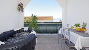 Ein Balkon mit Whirlpool, einem Tisch mit Früchten und Meerblick.