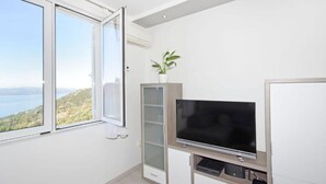 Ein modernes Zimmer mit großem Fenster, Flachbildfernseher und einer kleinen Pflanze.