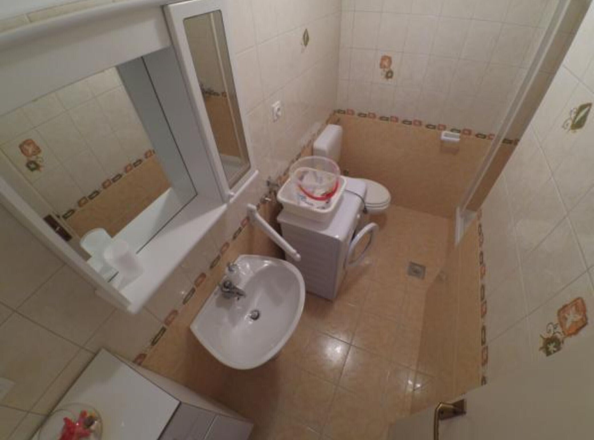 A small bathroom with a sink, toilet, and mirror.