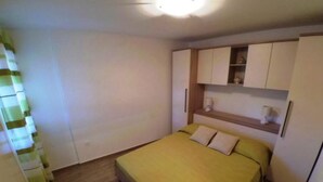 A small, neatly arranged bedroom with a bed, a nightstand, and built-in storage cabinets. - Apartments Maritimo - Two Bedroom Apartment with Sea View and Terrace (Smokvica)