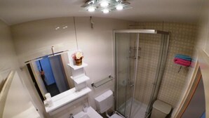 Une petite salle de bain comprenant une douche, des toilettes et un lavabo.