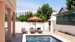 A swimming pool with lounge chairs and a red umbrella. - Villa Casa Mia Sabunike A2 (Privlaka)