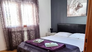 A bedroom with a bed, a nightstand, a lamp, and a painting on the wall. - Villa Casa Mia Sabunike A2 (Privlaka)