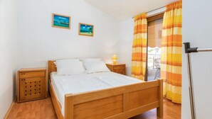 A bedroom with a wooden bed, two bedside tables, a nightstand, and a window with curtains. - Apartments Manda - One Bedroom Apartment With Terrace (A1) (Fazana)