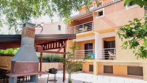 Ein Wohngebäude mit einer Terrasse, die einen Grill und eine Pergola hat.