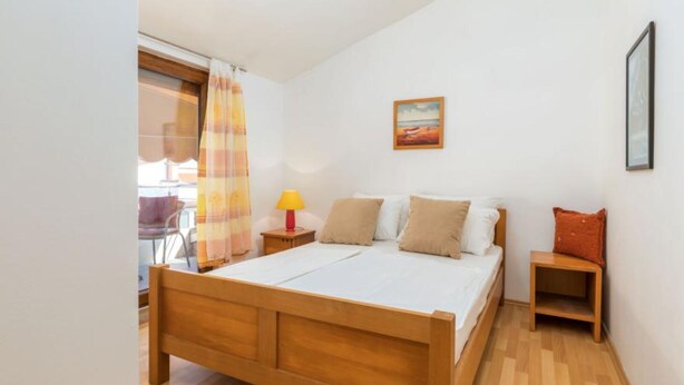 Une chambre à coucher avec un lit en bois, une table de chevet avec une lampe, une petite table et une chaise.