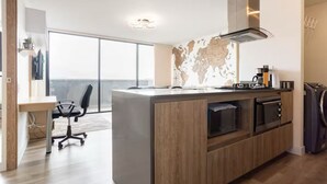 A modern kitchen with a large island, built-in oven, microwave, and a world map backsplash. - The Remote Work Dream (Medellín)