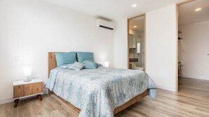 A bedroom with a bed, bedside table, and an air conditioning unit. - The Remote Work Dream (Medellín)