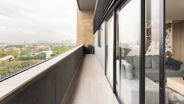 A balcony with a city view, a sofa, and a sliding glass door. - The Remote Work Dream (Medellín)