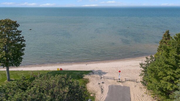 Une plage offrant une vue dégagée sur l’océan, un sentier sablonneux menant à l’eau et une petite construction en bois.