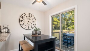 Un coin repas avec une grande horloge murale, une table et un banc.