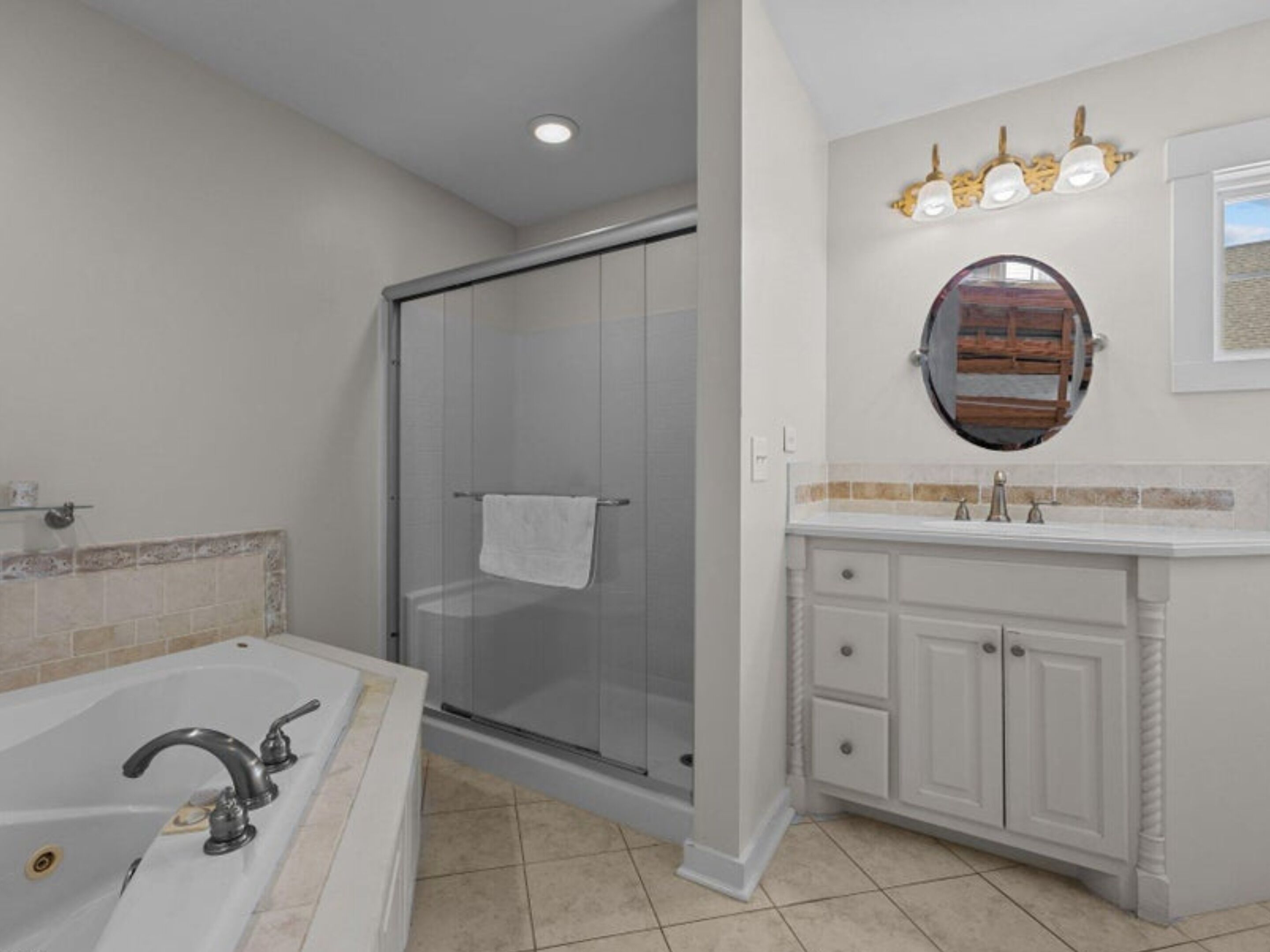 A bathroom with a walk-in shower, a bathtub, a vanity with a mirror, and a light fixture above the mirror.