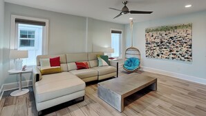 Een moderne woonkamer met een hoekbank, een hangstoel, een salontafel en een kunstwerk aan de muur.