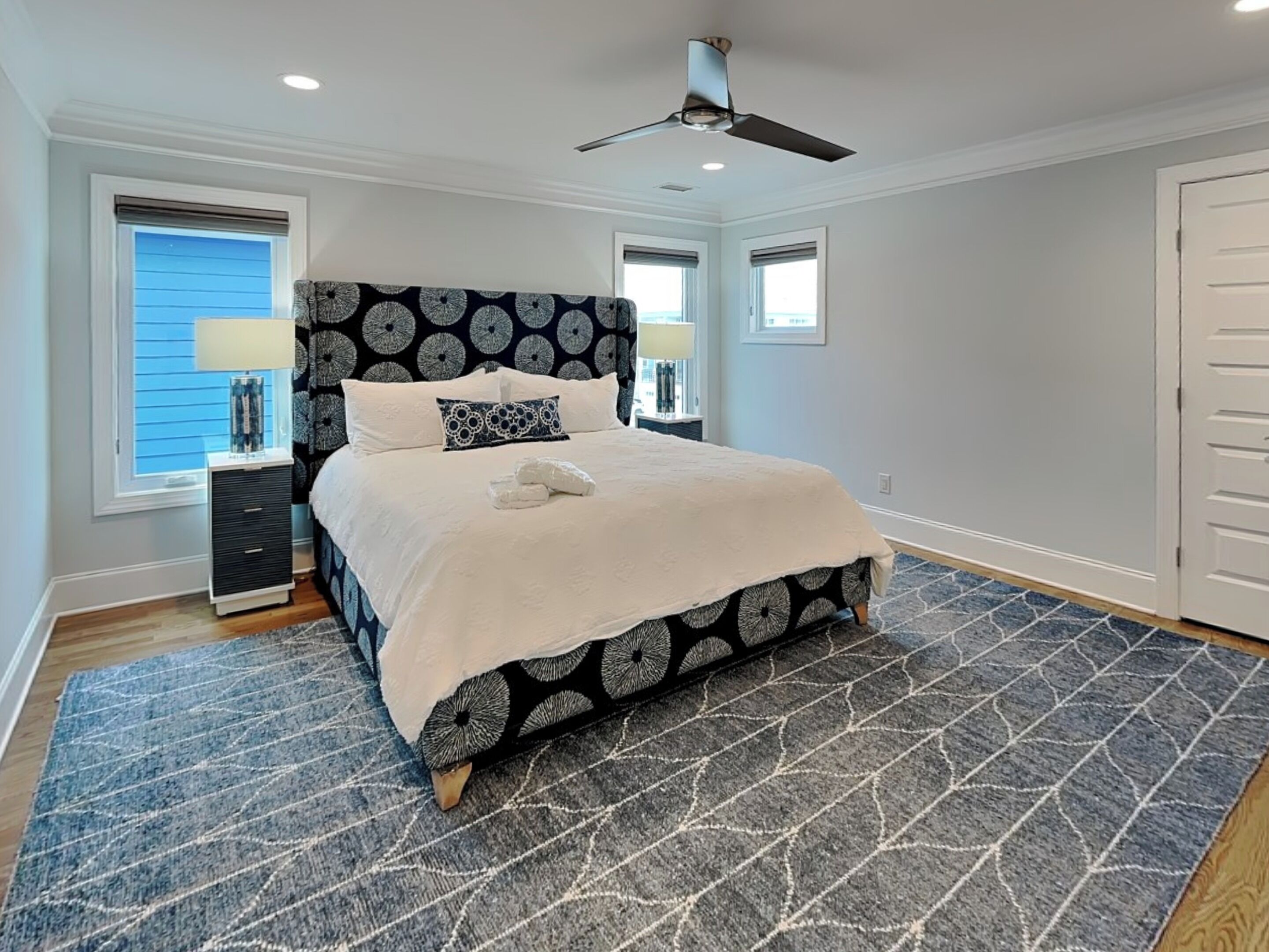 A bedroom with a bed, two bedside tables, a ceiling fan, and a window with blinds.