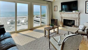 A spacious living room with a large sliding glass door leading to a balcony overlooking the ocean. - Riptide by Topsail Realty (Holly Ridge)