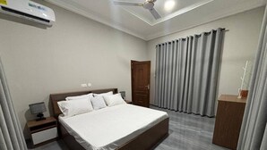 Une chambre d’hôtel moderne, dotée d’un grand lit, d’une table de chevet, d’un bureau et d’une armoire.