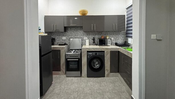 Une cuisine compacte équipée d’un lave-linge et d’un sèche-linge intégrés, d’une cuisinière et d’un four à micro-ondes.
