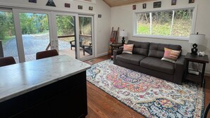 A spacious living area with a large window, a sofa, a coffee table, and a rug.
