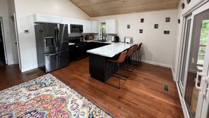 A modern kitchen with a central island, stainless steel appliances, and a wooden ceiling.