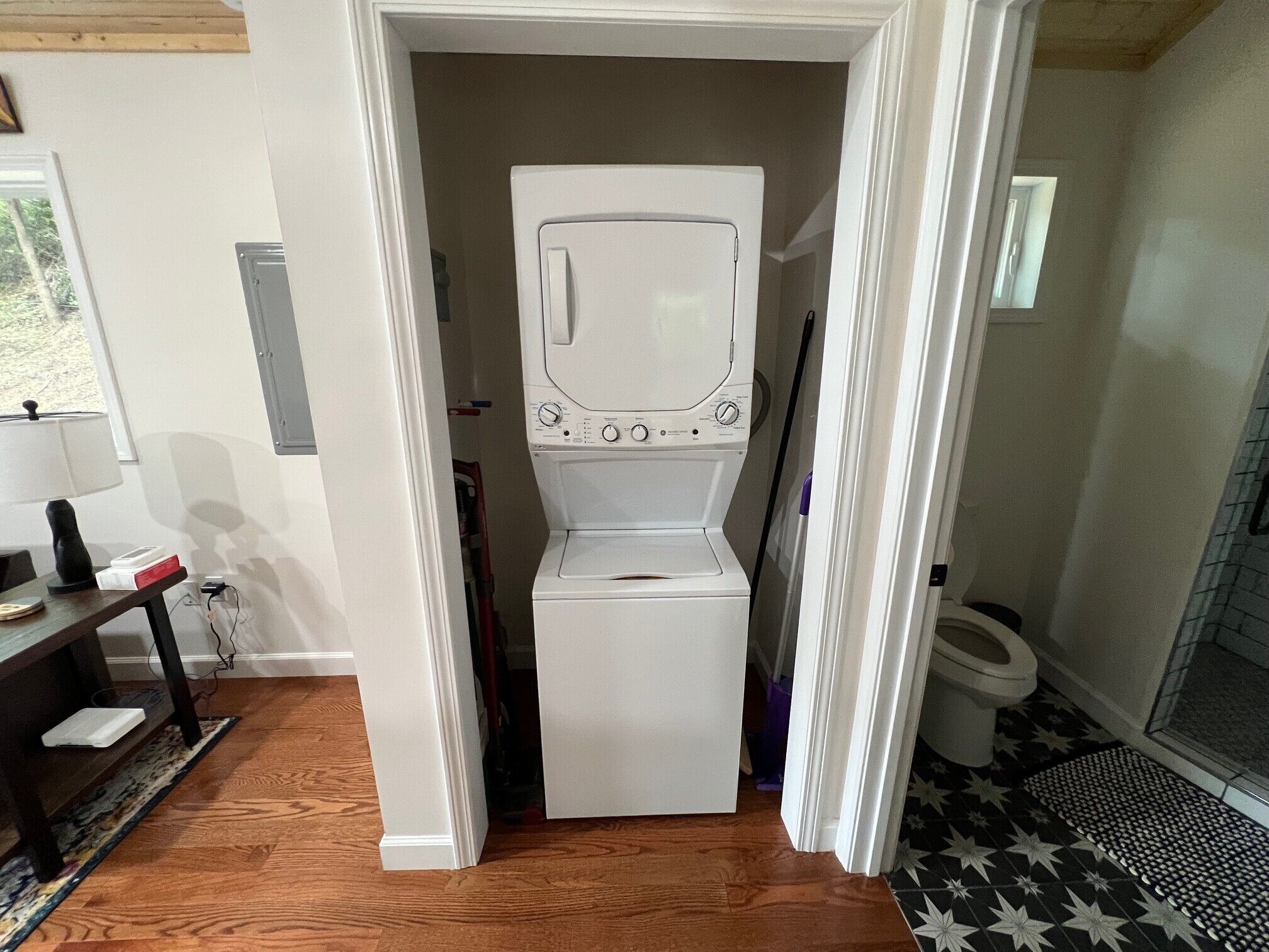 A compact bathroom with a white toilet, a washing machine, and a shower area.