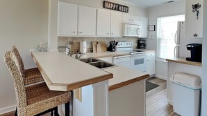 A modern kitchen with white cabinets, a wooden island, and a 'Happy Hour' sign.