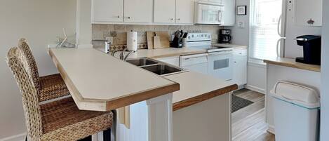 A modern kitchen with white cabinets, a wooden island, and a 'Happy Hour' sign.