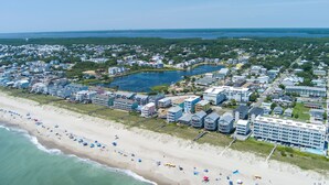An aerial view of a coastal town with a beachfront, residential buildings, and a large hotel.