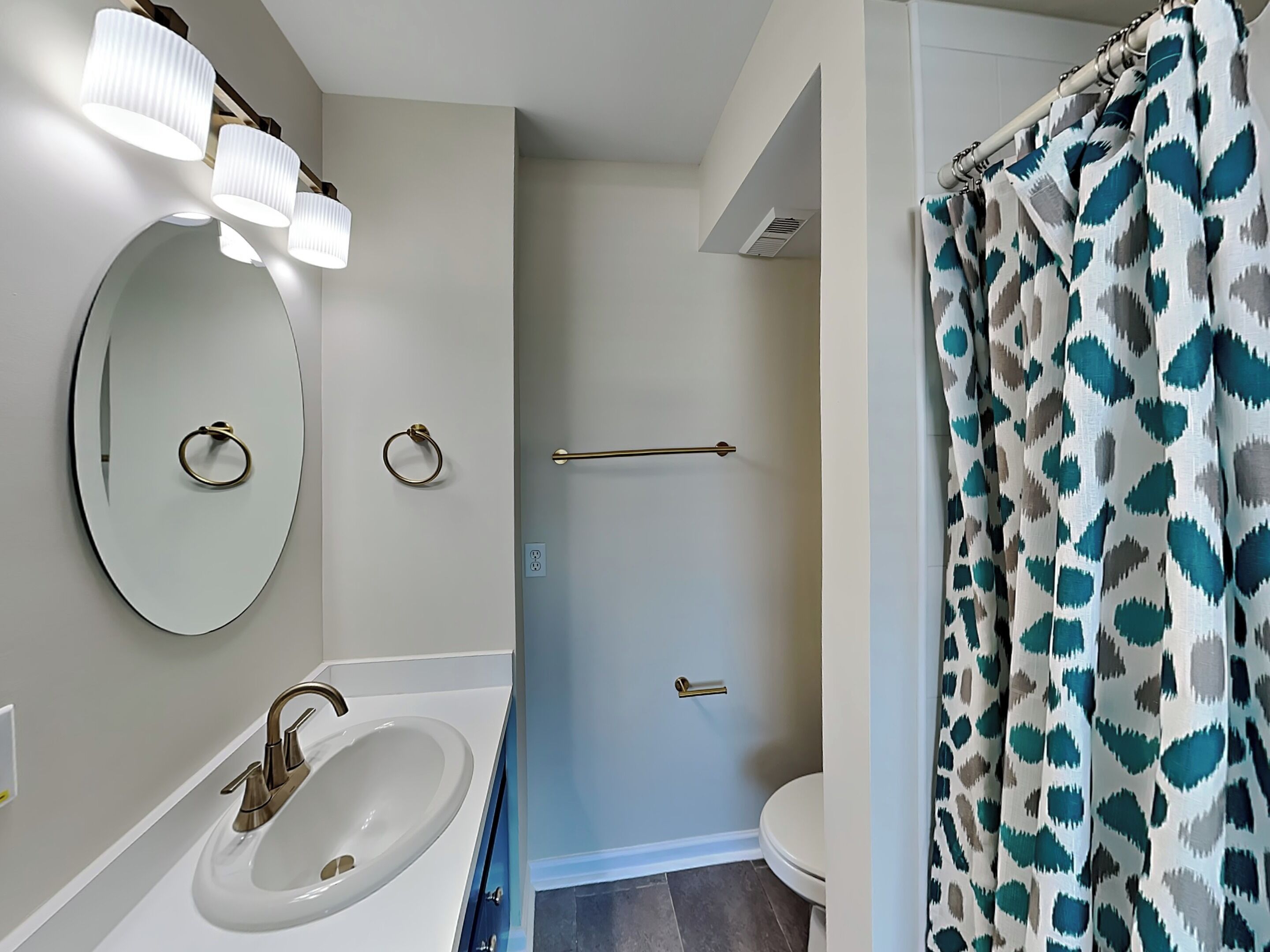 Une salle de bain équipée d’un lavabo, d’un miroir, de porte-serviettes et d’un rideau de douche.