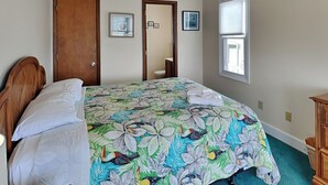 Une chambre à coucher avec un lit, une tête de lit en bois, une porte, une fenêtre et une commode.