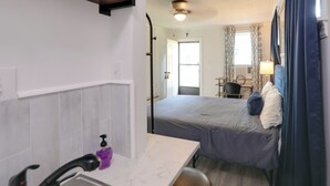 Una habitación compacta con cama, una mesita, un lavabo y una ventana con cortinas.