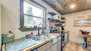 A kitchen with a large window, wooden countertops, a sink, and a microwave. - Lake Eufaula Access: Cozy Wood Cabin w/ Yard! (Abbeville)