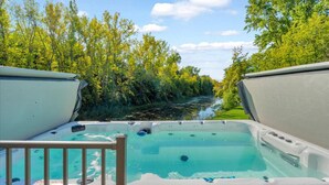 A hot tub with a view of a river and trees. - River’s Bend Sanctuary- WALK to Beach & Downtown (Caseville)