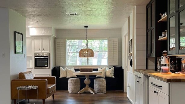 A spacious kitchen with a dining area, wooden flooring, and a large window. - Retreat @ The One | Movie Theater | Coffee Bar (Conroe)