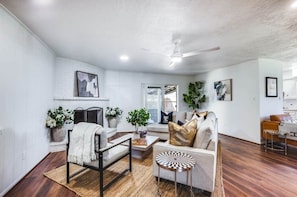 Sala de estar com sofá, poltrona, mesa de centro e ventilador de teto.