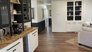 A modern kitchen with dark cabinets, a wooden countertop, and a coffee machine. - Retreat @ The One | Movie Theater | Coffee Bar (Conroe)
