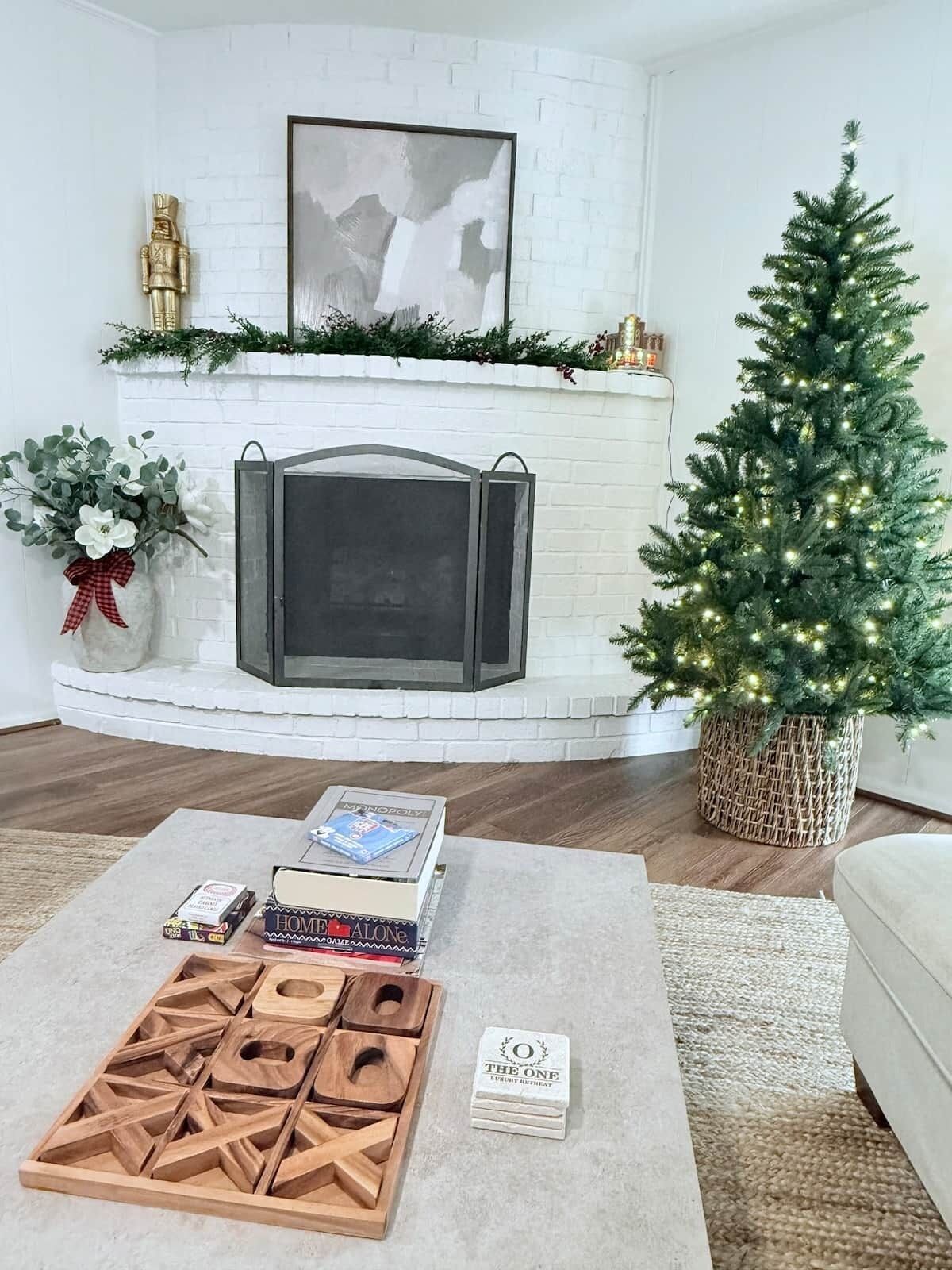 A living room with a fireplace, a Christmas tree, and a board game on a coffee table.