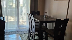 A dining area with a wooden table and chairs, a glass on the table, and a painting on the wall. - Rustic-Chic 2 bdr Pet Friendly Log Cabin, Steps to Lake Huron (Au Gres)