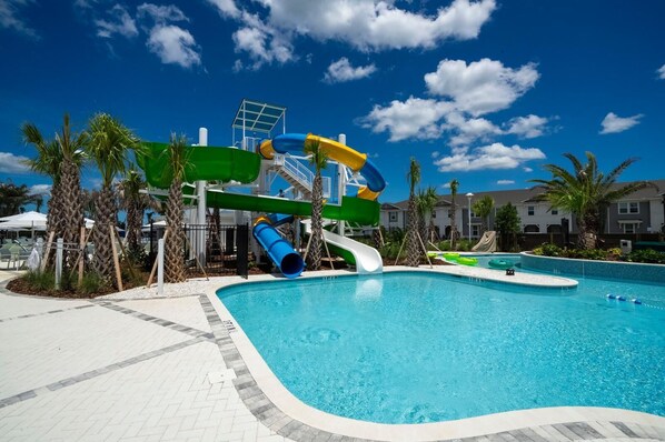 Una piscina con tobogán y palmeras.