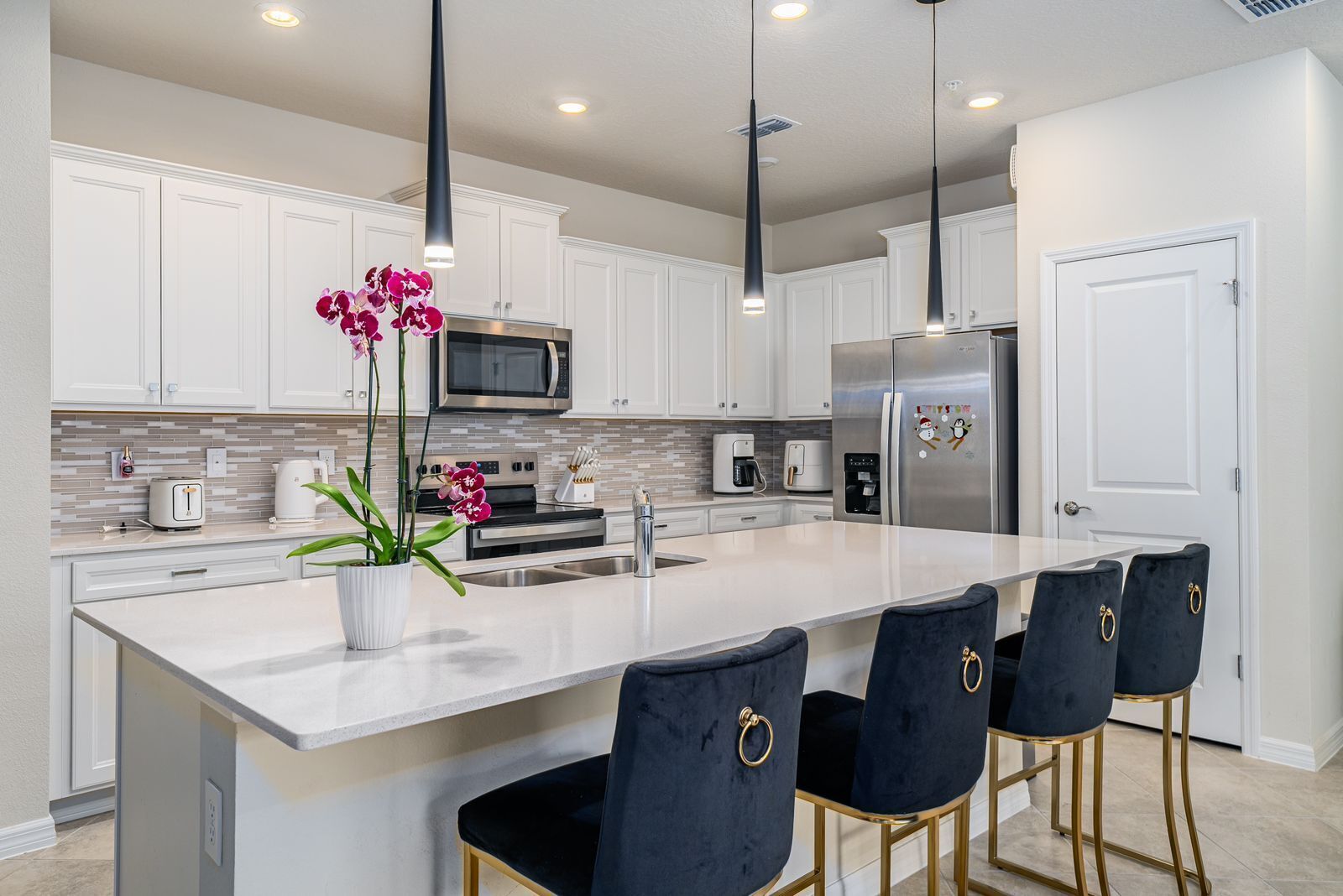 A modern kitchen with white cabinets, stainless steel appliances, and a central island with bar stools.