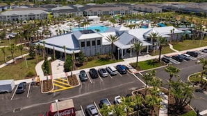 Un hotel con piscina central, amplios espacios de estacionamiento y una zona ajardinada con palmeras.