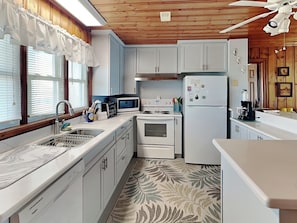 A kitchen with white cabinets, a microwave, a stove, and a refrigerator. - Pana-Sea-A by Topsail Realty (Holly Ridge)