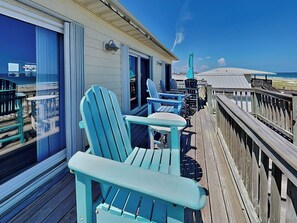 A wooden deck with blue Adirondack chairs and a railing overlooking the beach. - Piccolo Paradiso by Topsail Realty (Holly Ridge)