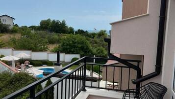 A balcony with a pool view, two chairs, and a small table.